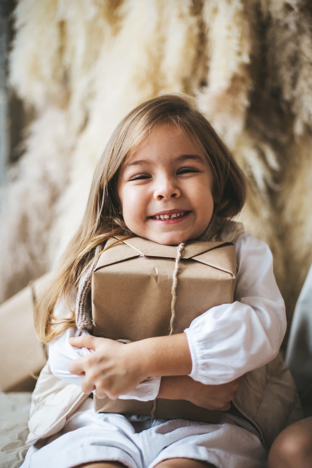 A smiling child hugging a wrapped gift